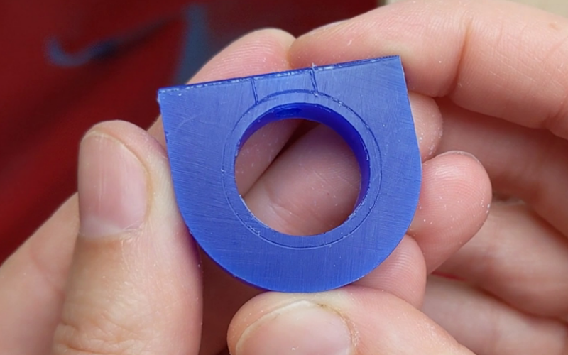 Close up of hands showing a blue wax ring blank with the shape of the finished ring marked on it 