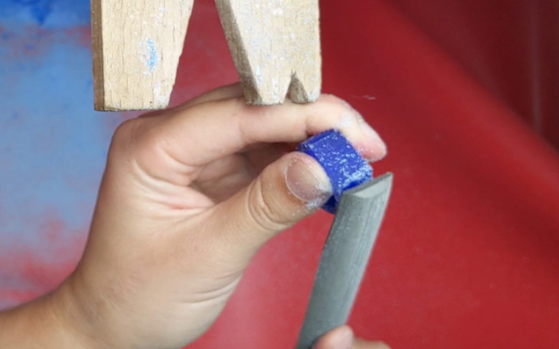 Close up of hands filing a piece of blue wax