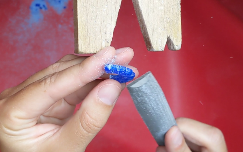 close up of hands filing a piece of blue wax