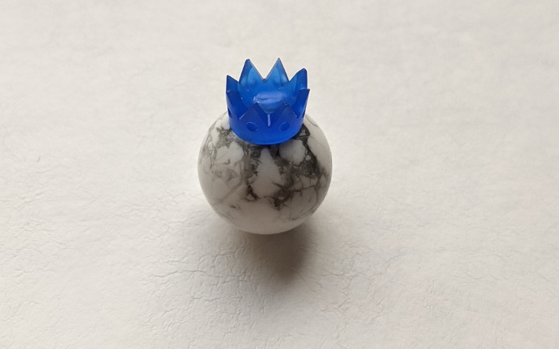 Bead with a beadcap that is shaped like a crown on top. Beadcap is made from blue wax 