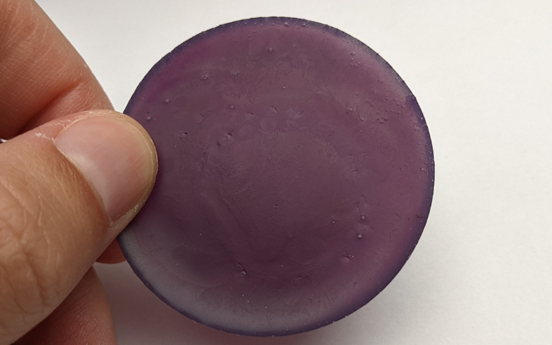 Round piece of newly melted purple wax. It has a lot of visible air bubbles inside