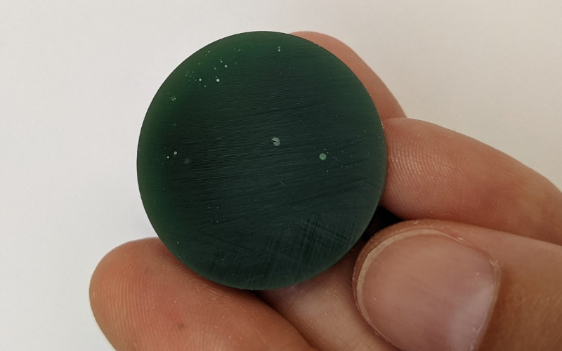 Piece of round green wax with visible air bubbles inside the wax 