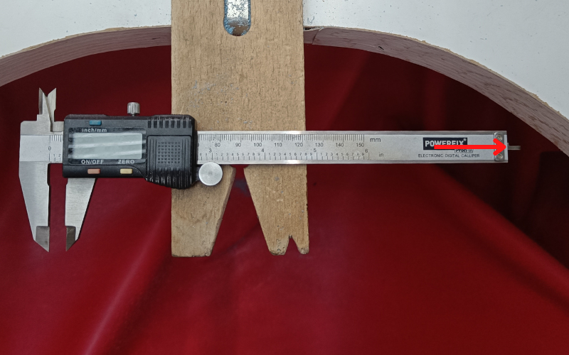 Bench peg with calipers on them. The calipers are slightly open so you can see the stick part slide out at the back. There's a red arrow pointing to it