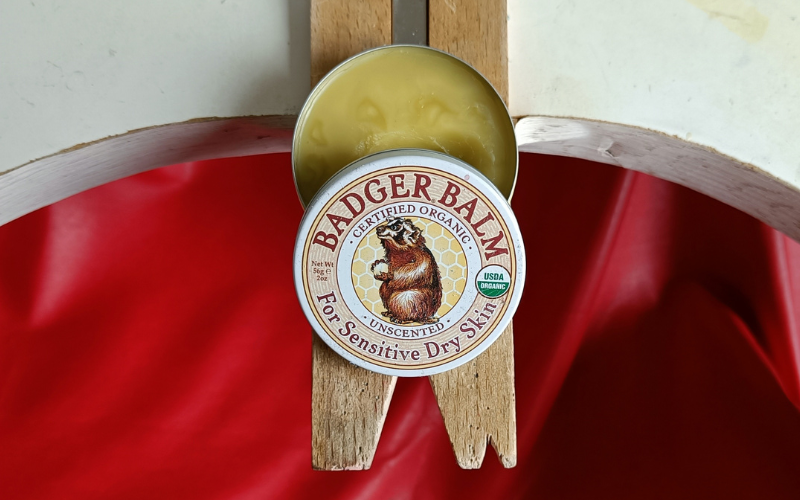 Close up of an open tin of badger balm on a bench peg