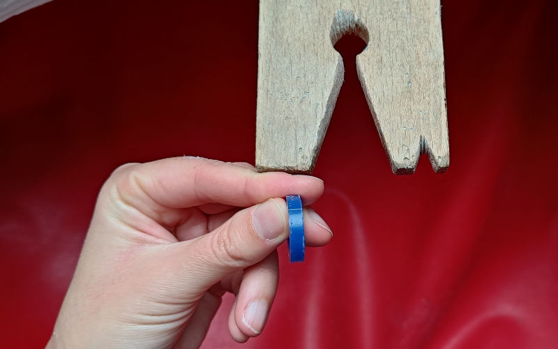 Bench peg with forefinger of left hand braced against it. Forefinger and thumb are holding a blue wax ring. The ring is not touching teh benchpeg 