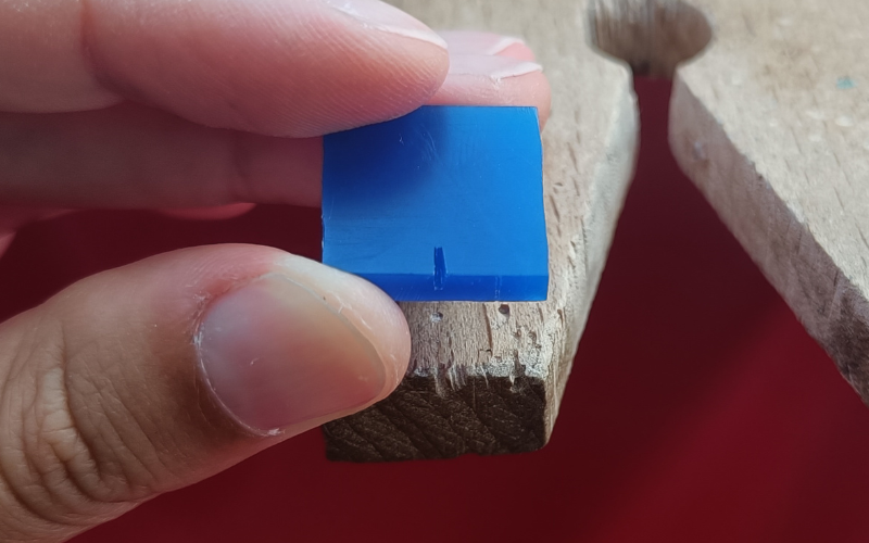 Piece of wax with the small V made into a bigger, straighter and deeper gap