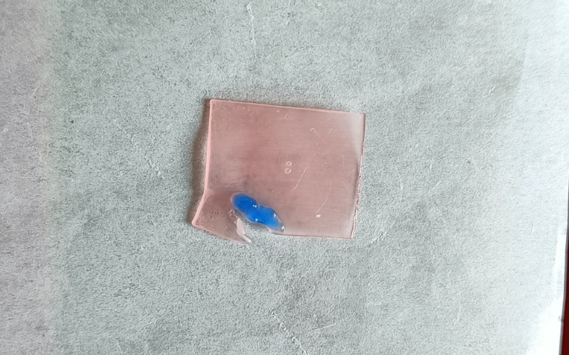 Piece of pink sheet wax with hard blue wax melted on top. The sheet wax is broken right next to the blue wax because it became to hot 