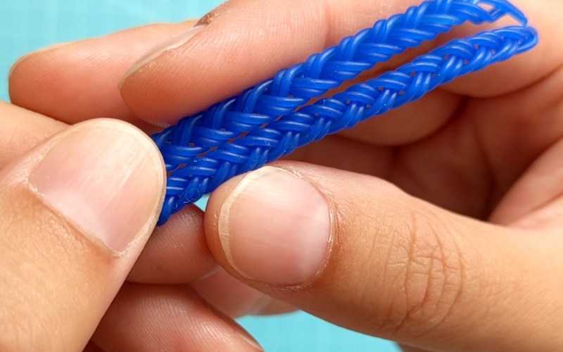 Closeup of hands holding 2 lengths of braided wax wire 