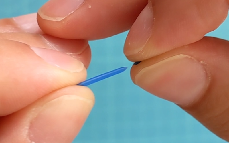 CLose up of hands holding a piece of broken blue wax wire