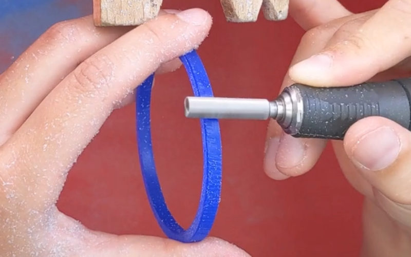 Close up of hands burring the outside of a blue wax bangle 