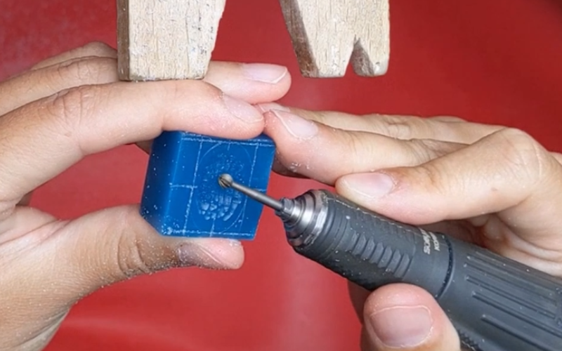 Close up of hands working at the bench burring a piece of turquoise wax