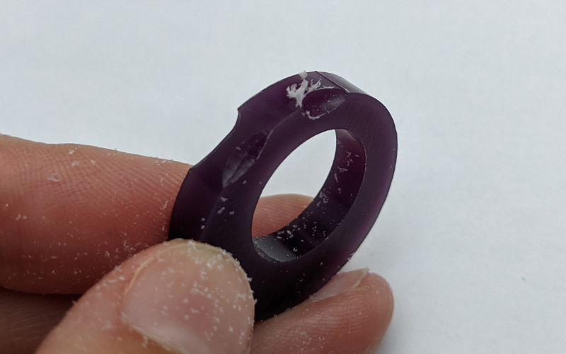 Purple ring with burr marks. One of the burr marks has wax dust clinging to the edge