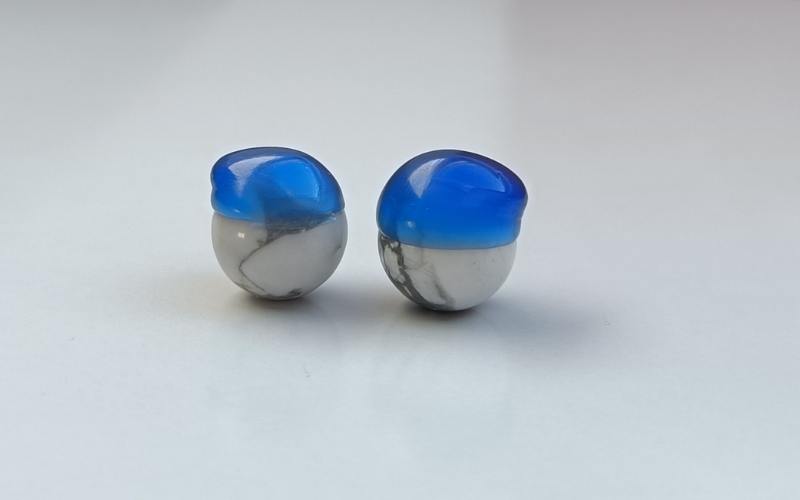  Close up of 2 howlite beads with freeform blue wax bead caps