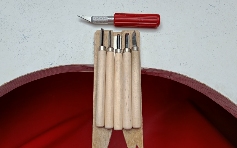 Bench with 5 carving toolsa and a stanley knife on top 