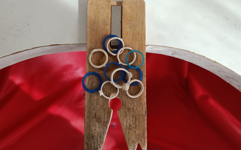 close up of bench peg with a variety of cast rings in silver and rings in blue wax, one ring is in turquoise wax