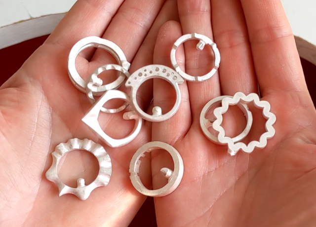 Close up of hands with a variety of silver uncleaned ring casting on top