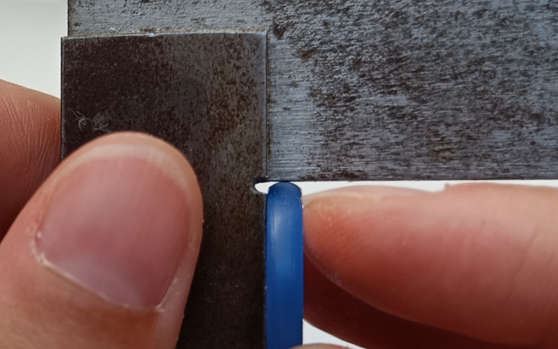 Close up of hands holding a set square and measuring a turquoise court shape ring