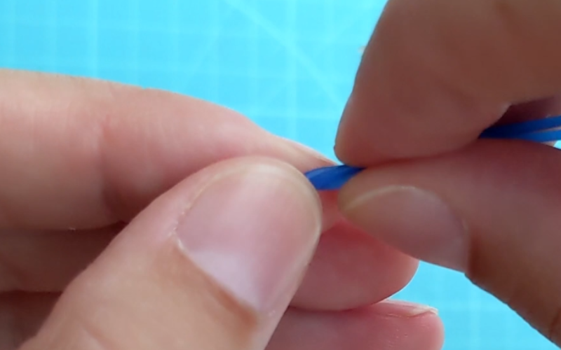 Close up of hands twisting wire, hands are close together and only small piece of wire is visible to work on 