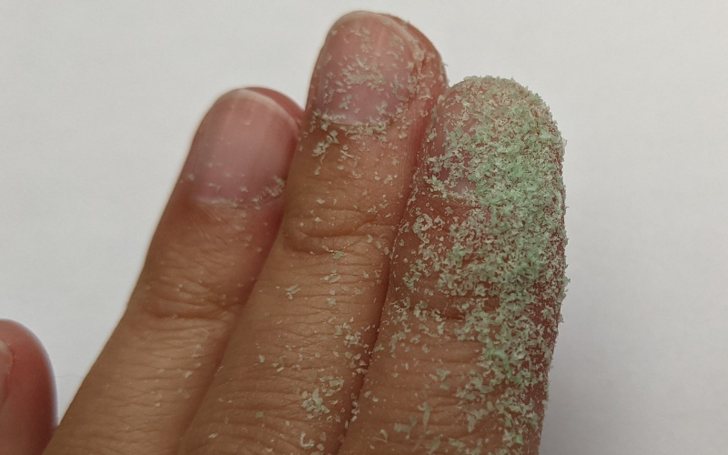 Fingers covered in coarser green wax dust