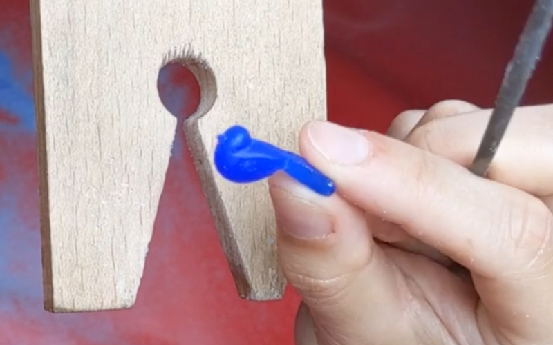 Close up of hand holding a half finished bird from blue wax