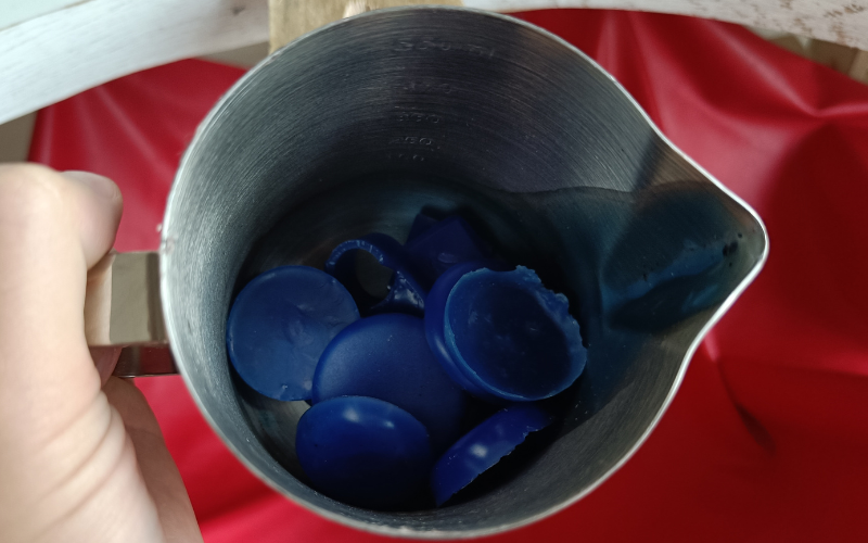 Close up of teh cup part of teh candle wax melter filled with blue wax