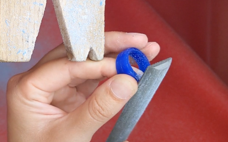 Close up of hands working at the bench filing a curve on the outside of the ring shank