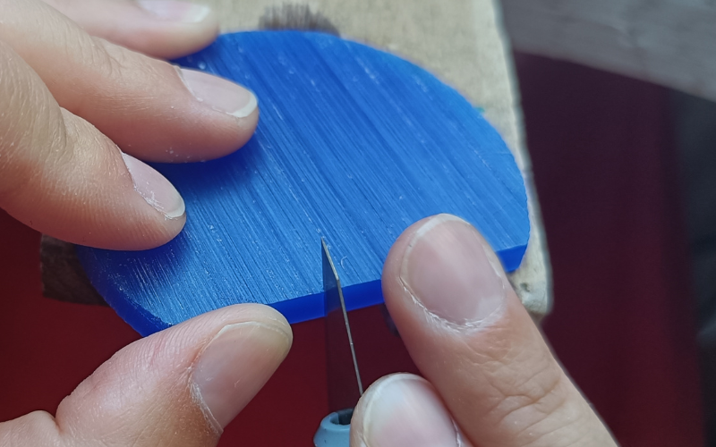 Piece of wax on a bench peg with a stanley knife inside it. The stanley knife is tilted down 