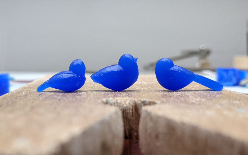 3 half finished birds in blue wax on a bench peg. All early attempts that have been abandoned for one reason or another