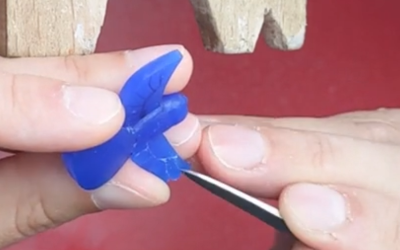 Close up of hands working on shaping the feathers on a bird wing