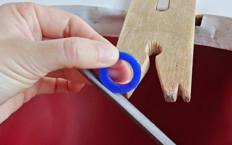 Close up of hands holding a piece of blue ring wax. Left hand is holding the ring in quarter 4, right hand is filing at quarter 3 which is in a more difficult to reach spot making filing uncomfortable