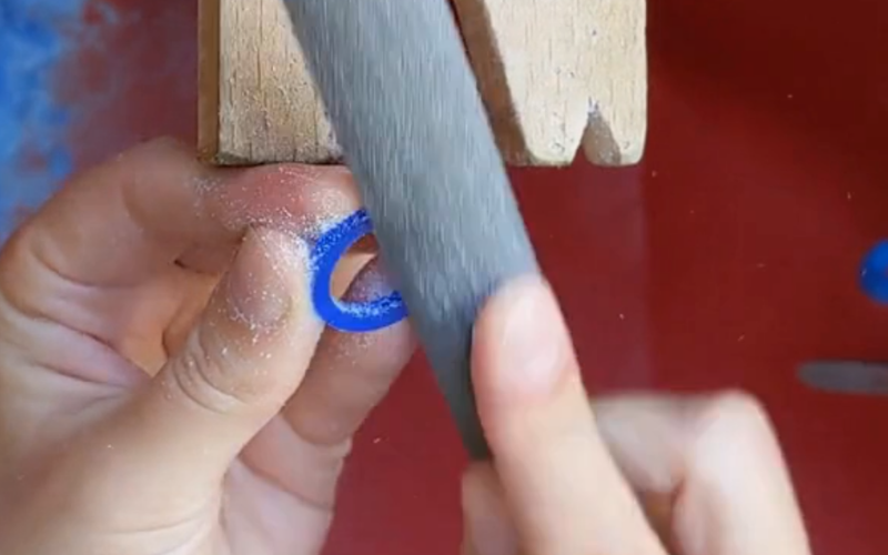 A bench peg and someone is filing the side of a ring