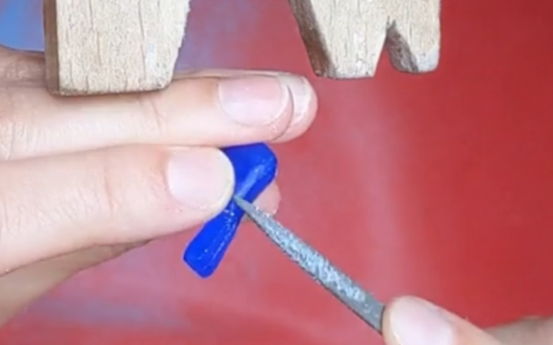 Close up of hands working on a blue wax bird