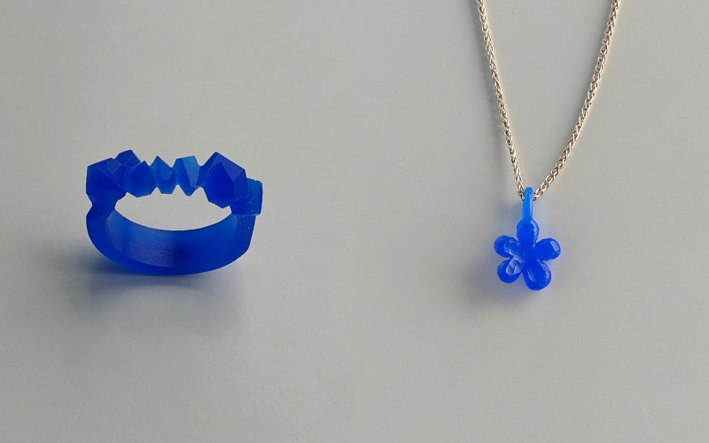 blauwe wax ring met een gebeeldhouwde rotsachtige textuur bovenop, blauwe wax bloem hanger aan een zilveren ketting