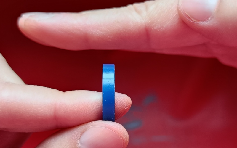 Close up of hands holding a piece of blue ring wax. One hand is flat over the wax to make it easier to see if the ring is flat or not