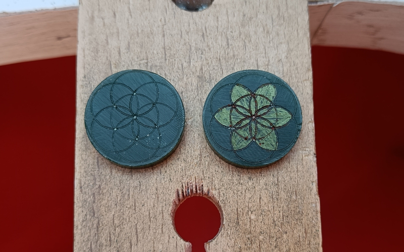 2 green pieces of wax with a flower pattern marked on. The right one has the flower colored in with pen to clarify the shape 