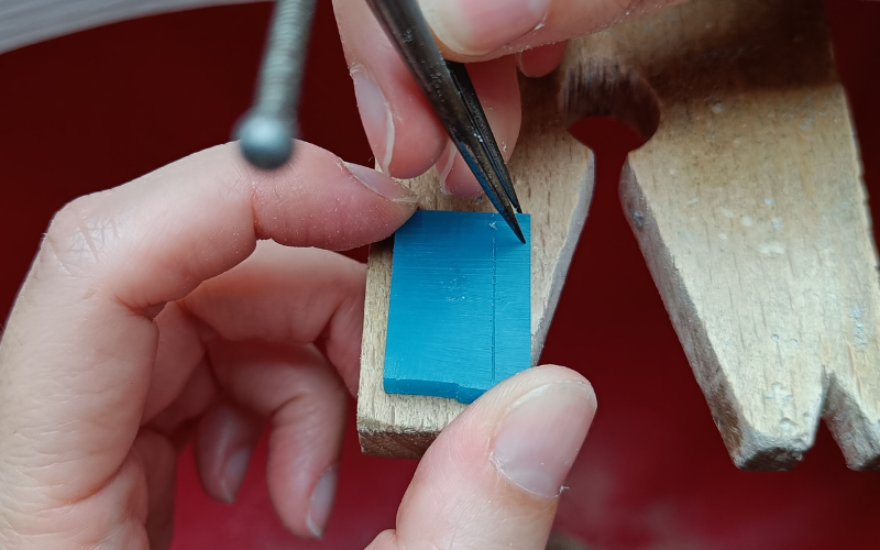 rectangle of wax with a line marked on teh right side. Hand holding dividers trying to mark a line on top