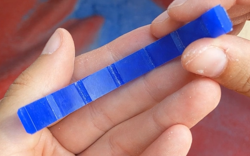 Close up of hands holding a blue wax bangle. You can see lines filed on the inside of the bangle