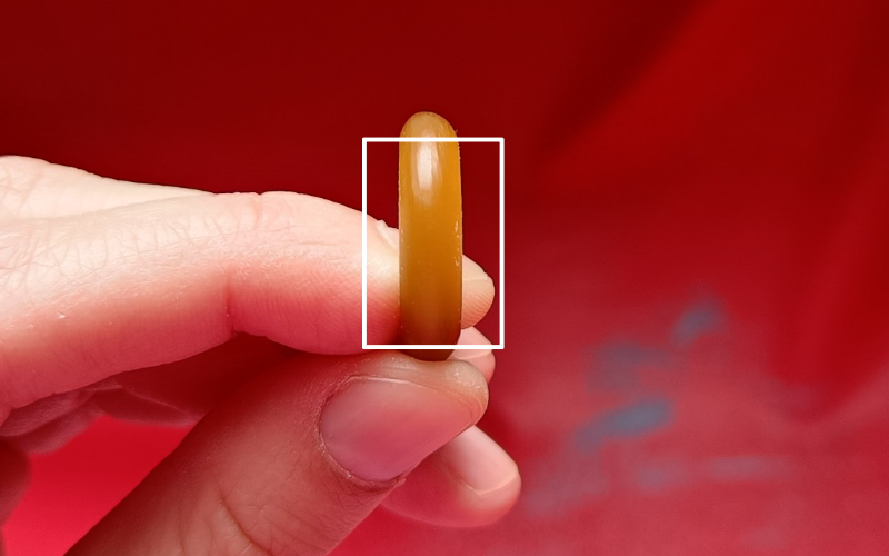 Close up of hands holding a piece of gold ring wax. A rectangle is drawn around the part that is right in front of you