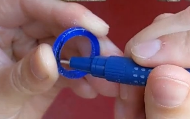 Hand holding a wax ring, other hand is coloring part of the ring with marker