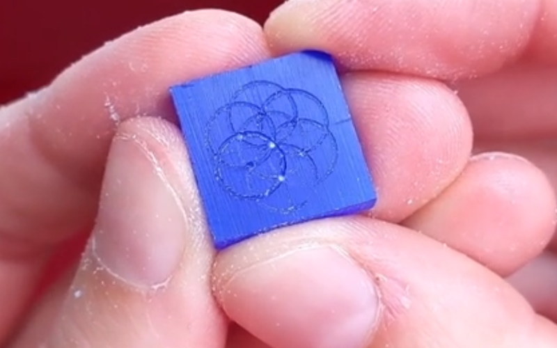 Close up of hands holding a piece of blue wax with a flower pattern marked on it