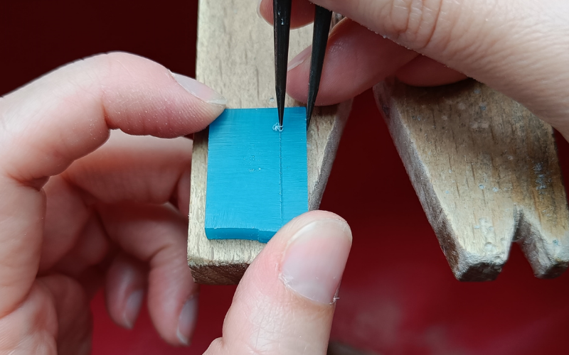 rectangle of wax hand holding dividers marking a line on the right