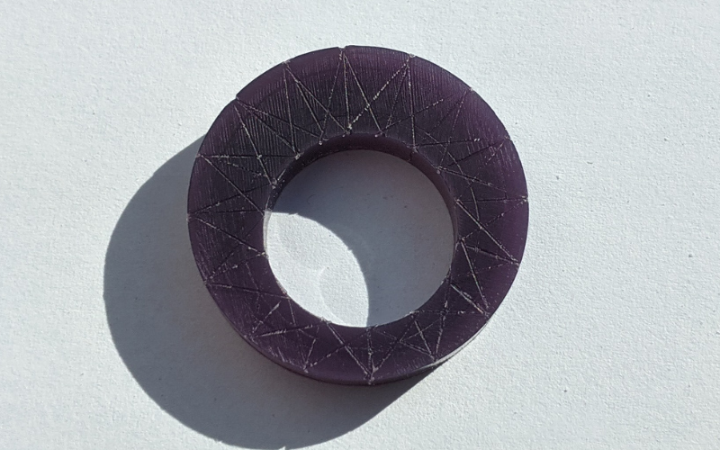 Purple ring with spiky sunburst patterned marked on it. You can see the wax dust still in the marks