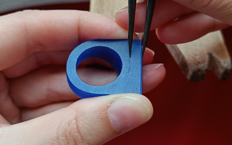 Close up of hands marking a line on a piece of blue ring tube using the outside as the guide