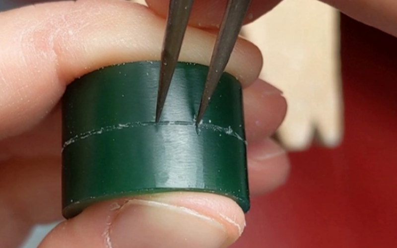 CLose up of hands marking out equal distances on the centre line of a green wax ring