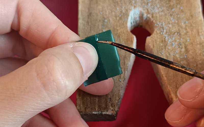 close up of hands holding pieces of green wax and melting  them together with a wax heating pen