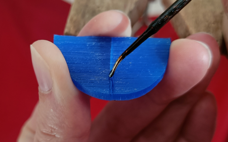 Close up of hands holding apiece of blue wax and melting it together with a wax heating pen