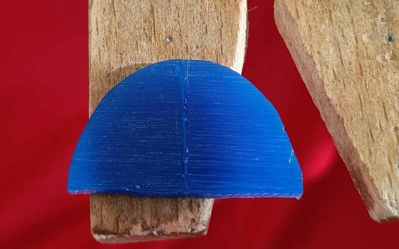 Close up of blue piece of wax that's melted together. The join is a raised through the centre