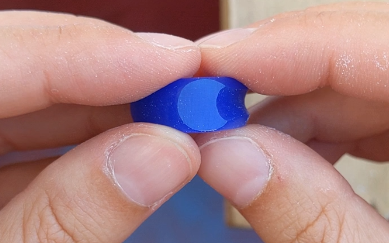 Close up of hands holding a blue wax signet ring, the signet is shaped to a crescent moon shape