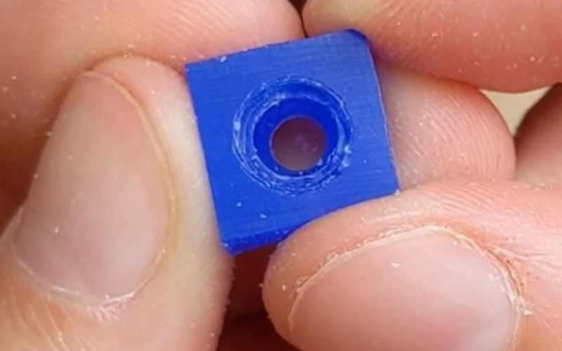 Close up of hands holding a piece of blue wax with a hole inside. the seat inside the hole is narrow