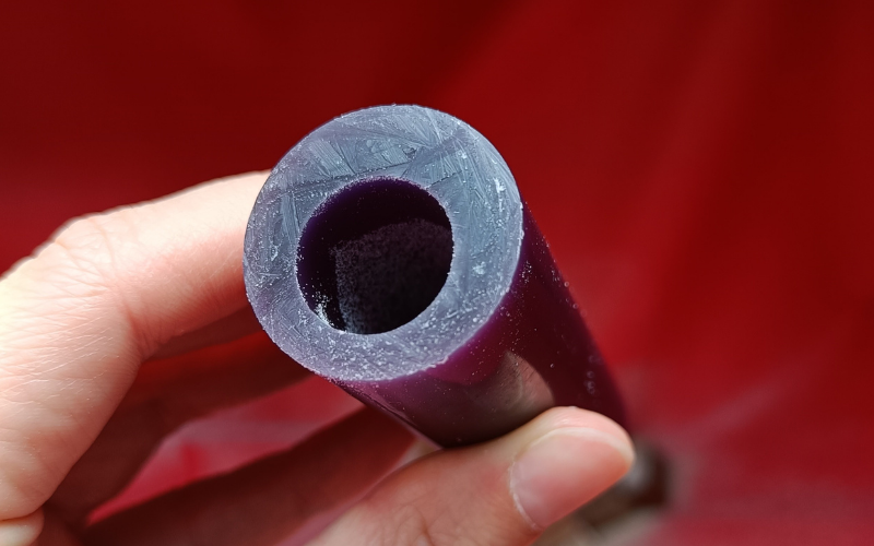 Hand holding a purple off-center ring tube 